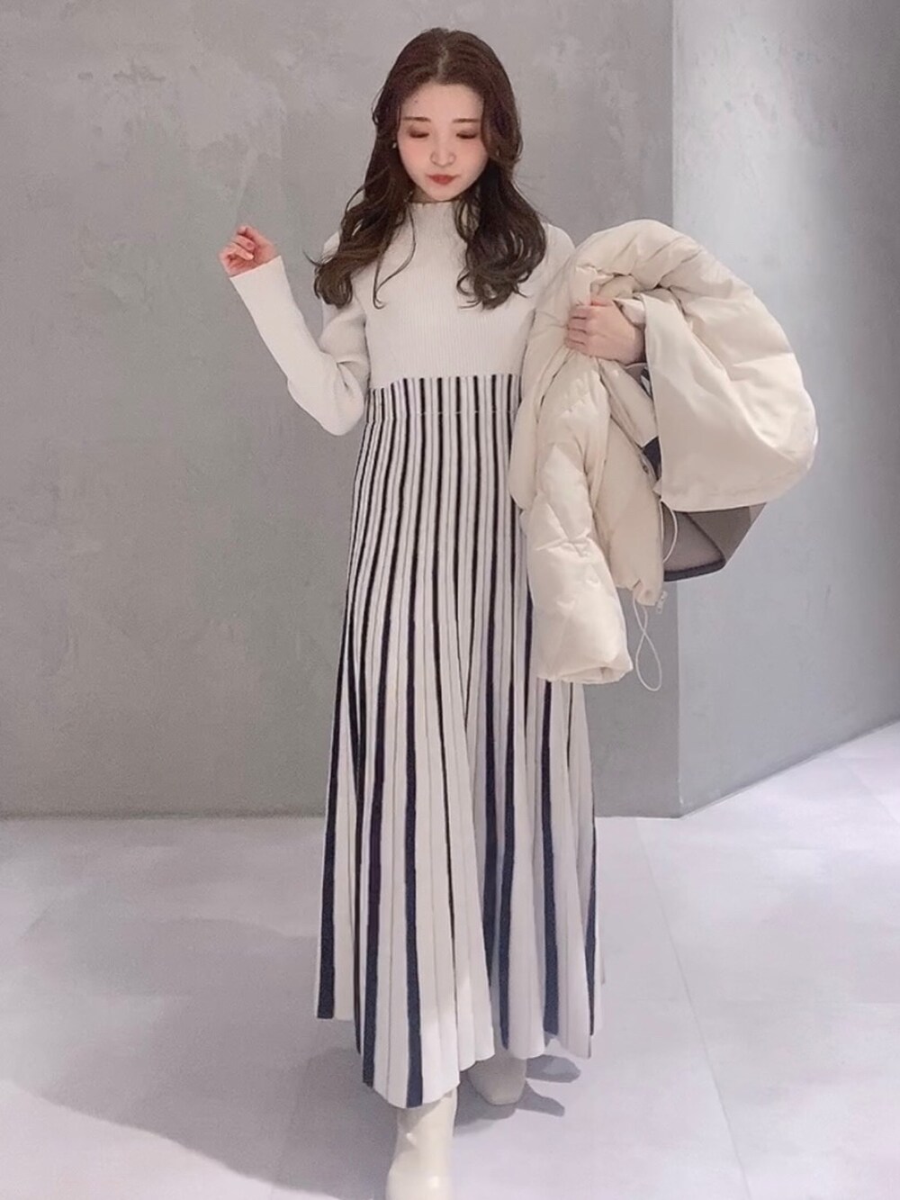 ホワイト系のワンピース、ホワイト系のブーツ、ブラウン系のハンドバッグを着用したレディースの冬コーディネートの6枚目の写真