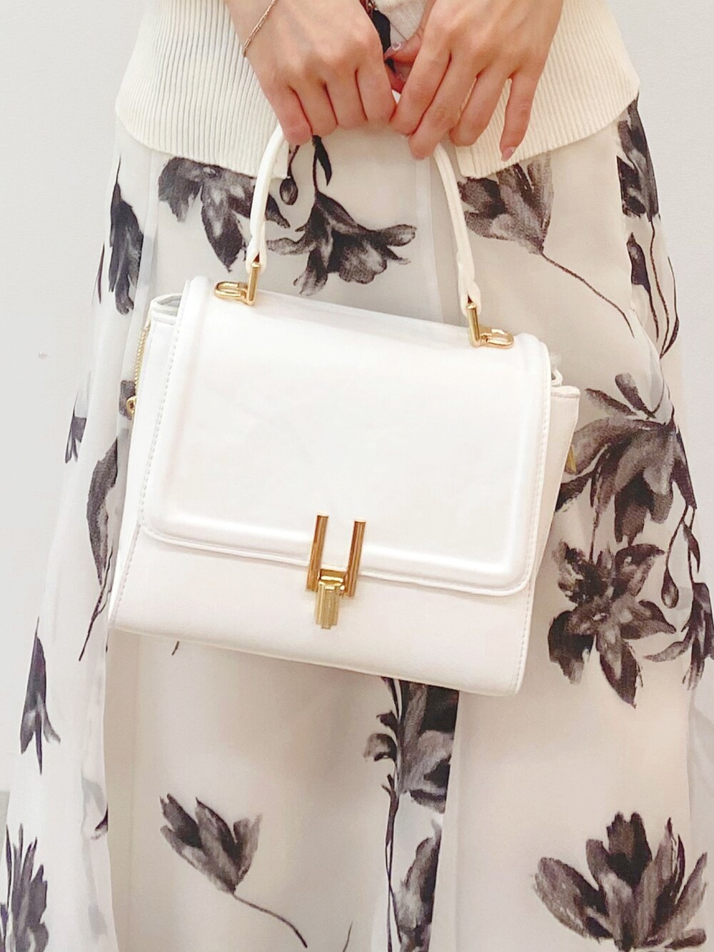 ホワイト系のニット/セーター、ホワイト系のスカート、ホワイト系のハンドバッグを着用したレディースの秋コーディネートの6枚目の写真