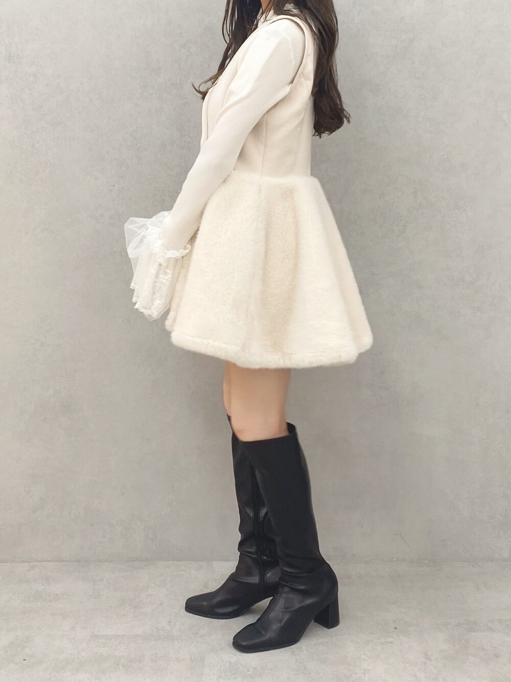 ブラック系のブーツ、ホワイト系のワンピース、ホワイト系のニット/セーターを着用したレディースの秋コーディネートの2枚目の写真