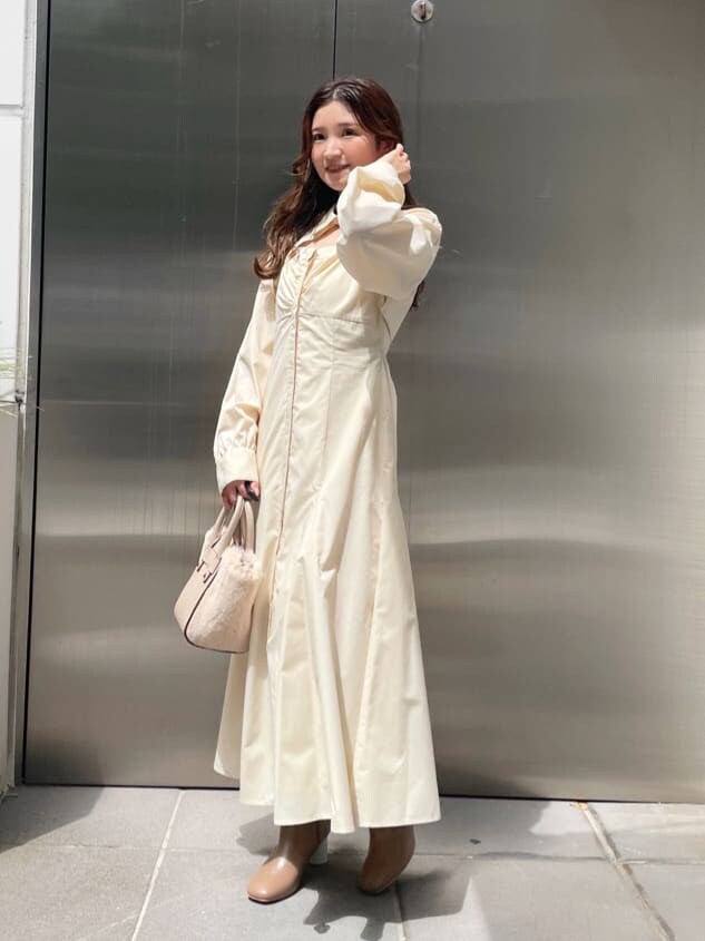 ベージュ系のブーツ、ホワイト系のハンドバッグ、ホワイト系のワンピースを着用したレディースの秋コーディネートの2枚目の写真