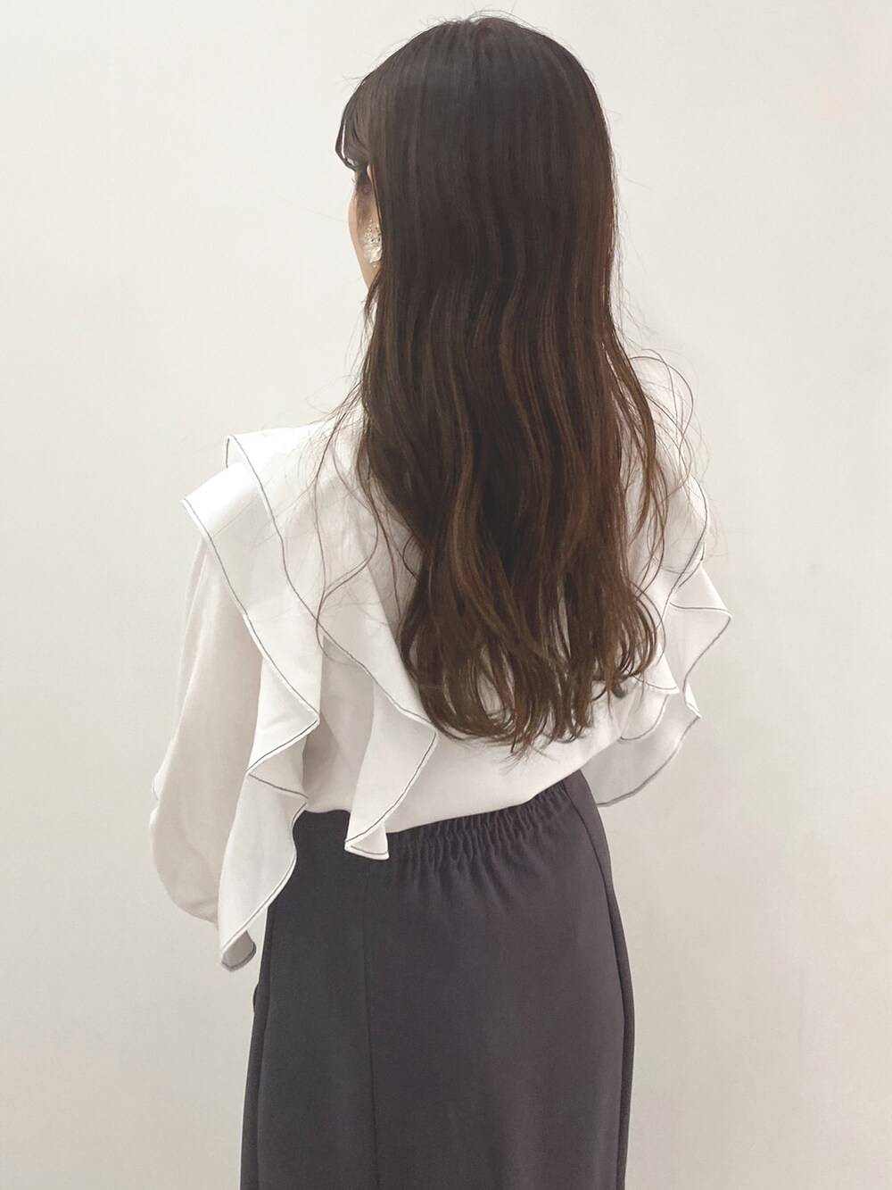 グレー系のスカート、ホワイト系のシャツ/ブラウス、ブラック系のハンドバッグを着用したレディースの冬コーディネートの4枚目の写真