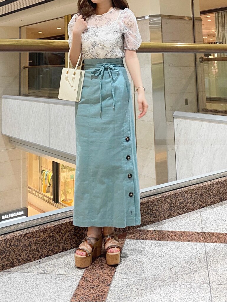 ベージュ系のトートバッグ、グリーン系のスカート、グリーン系のサンダルを着用したレディースの春コーディネートの2枚目の写真