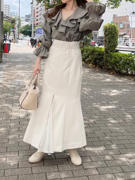 ホワイト系のスカート、ホワイト系のハンドバッグ、ホワイト系のブーツを着用したレディースの秋コーディネートの2枚目の写真