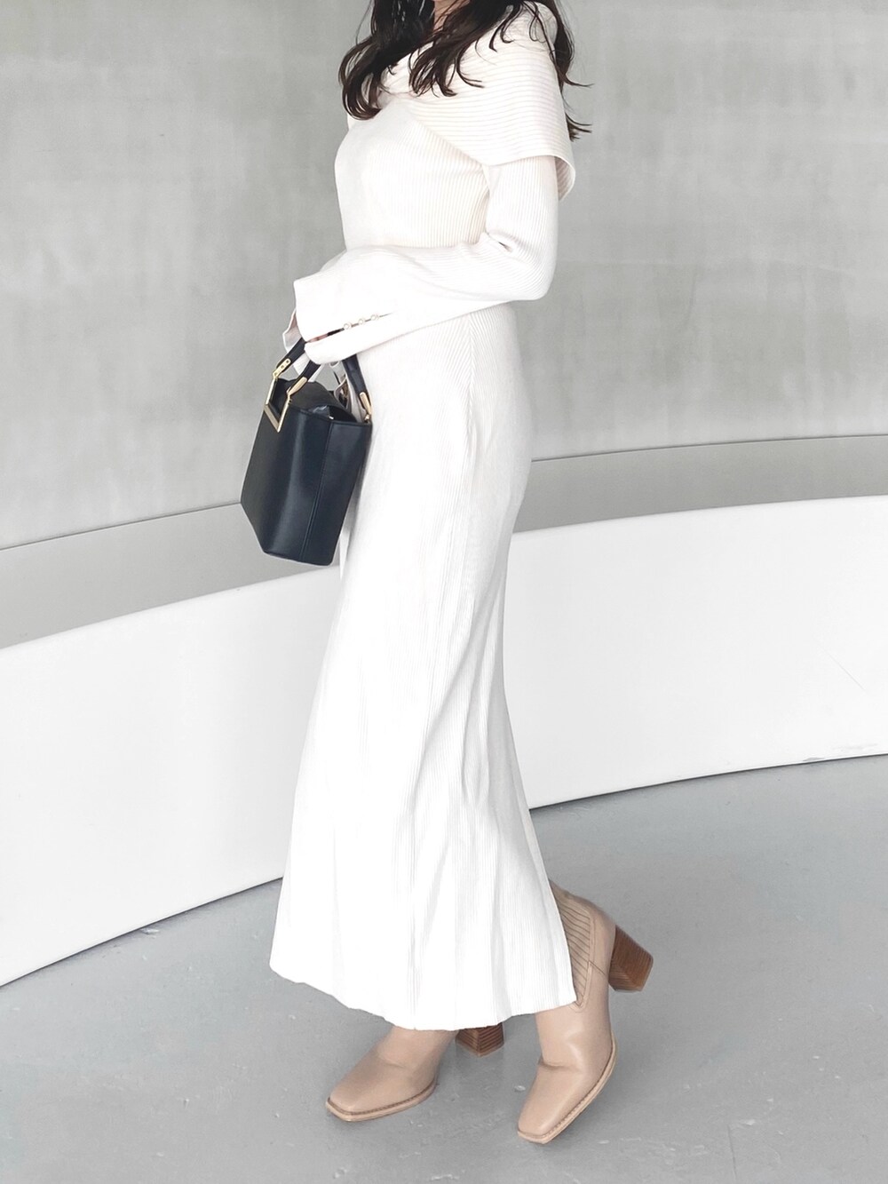 ホワイト系のワンピース、ブラック系のハンドバッグ、ベージュ系のブーツを着用したレディースの冬コーディネートの2枚目の写真