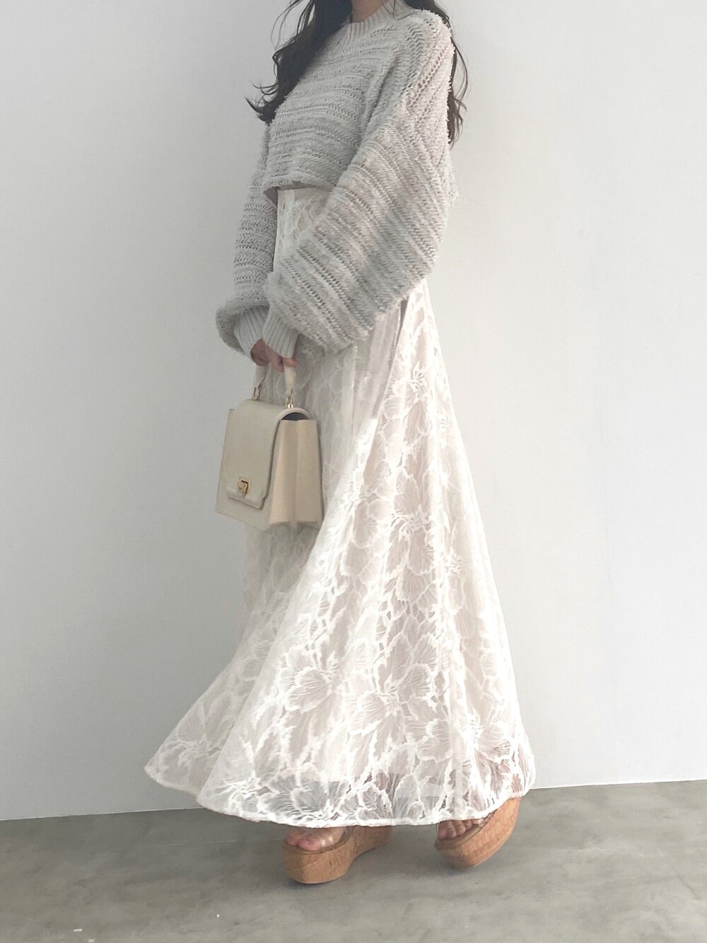 ホワイト系のサンダル、グレー系のニット/セーター、ホワイト系のハンドバッグを着用したレディースの冬コーディネートの2枚目の写真