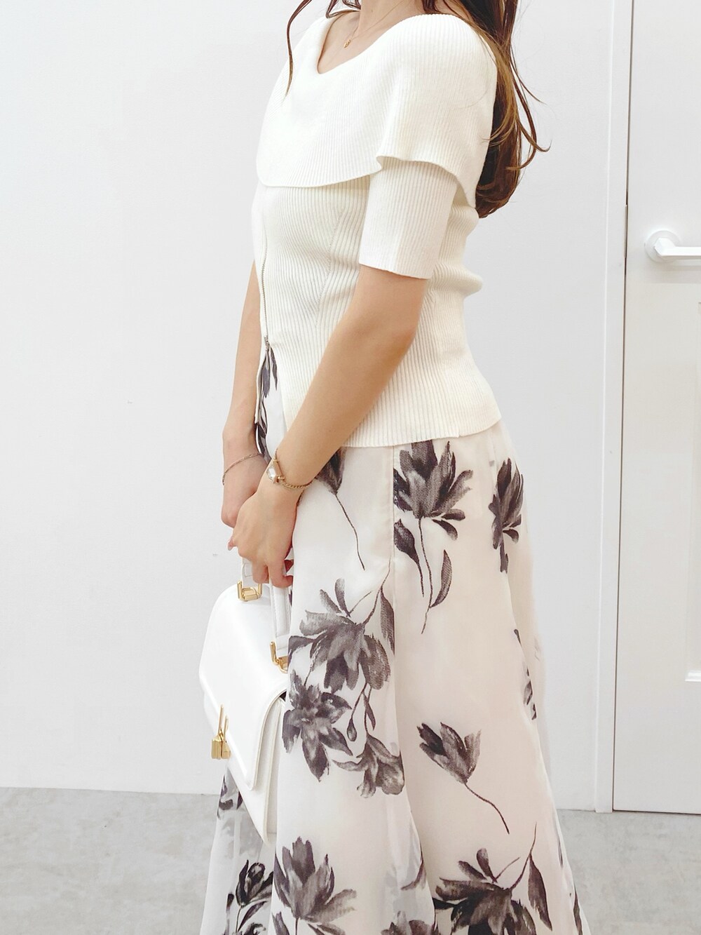 ホワイト系のニット/セーター、ホワイト系のスカート、ホワイト系のハンドバッグを着用したレディースの秋コーディネートの5枚目の写真