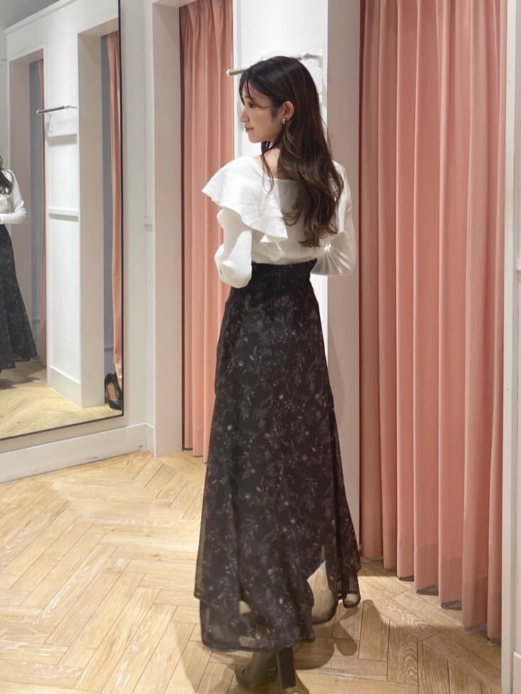 ブラック系のブーツ、ホワイト系のニット/セーター、ブラウン系のスカートを着用したレディースの秋コーディネートの2枚目の写真