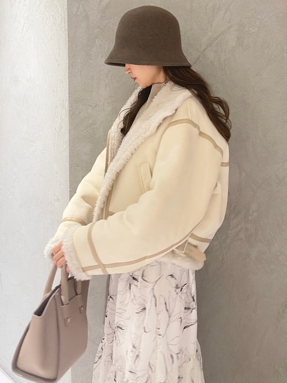 ホワイト系のムートンコート、ホワイト系のブーツ、ベージュ系のハンドバッグを着用したレディースの冬コーディネートの4枚目の写真