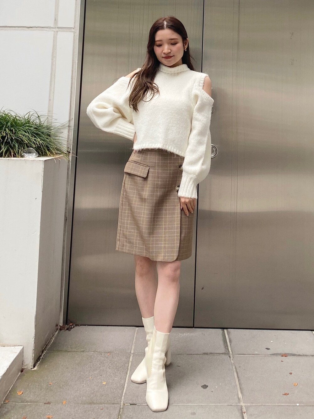 ホワイト系のニット/セーター、ベージュ系のスカート、ホワイト系のブーツを着用したレディースの秋コーディネートの8枚目の写真