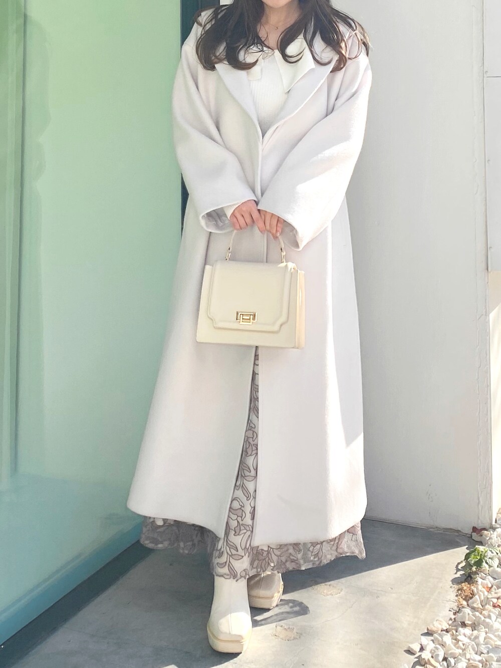 ホワイト系のブーツ、ホワイト系のハンドバッグ、ホワイト系のチェスターコートを着用したレディースの冬コーディネートの3枚目の写真