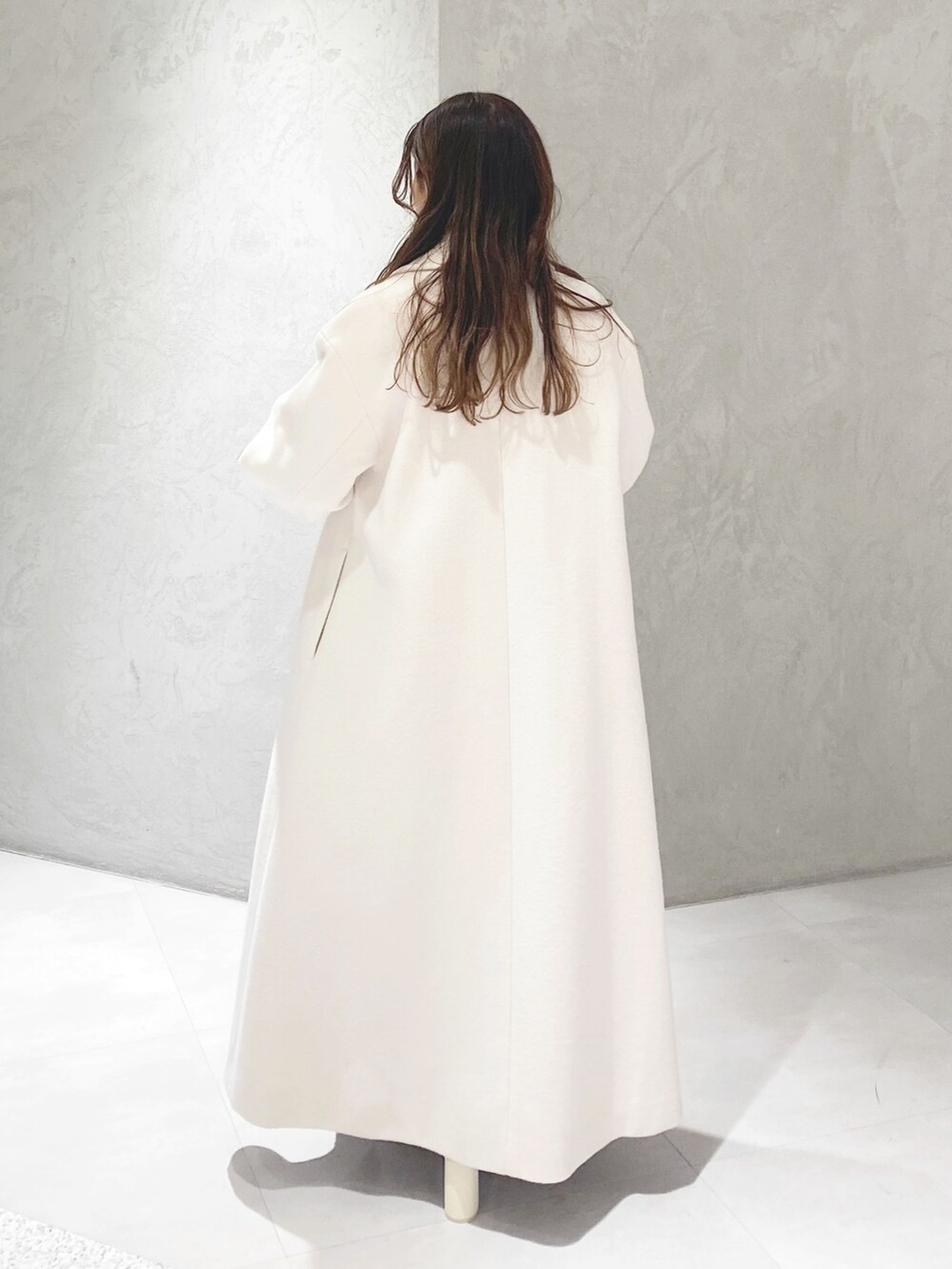 ホワイト系のチェスターコート、ホワイト系のブーツ、パープル系のニット/セーターを着用したレディースの冬コーディネートの7枚目の写真