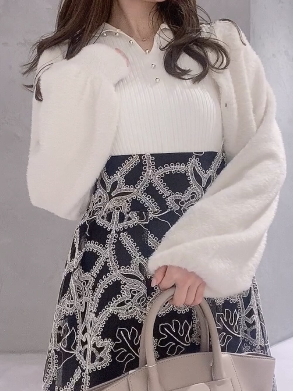 ベージュ系のハンドバッグ、ブラック系のスカート、ホワイト系のニット/セーターを着用したレディースの冬コーディネートの5枚目の写真