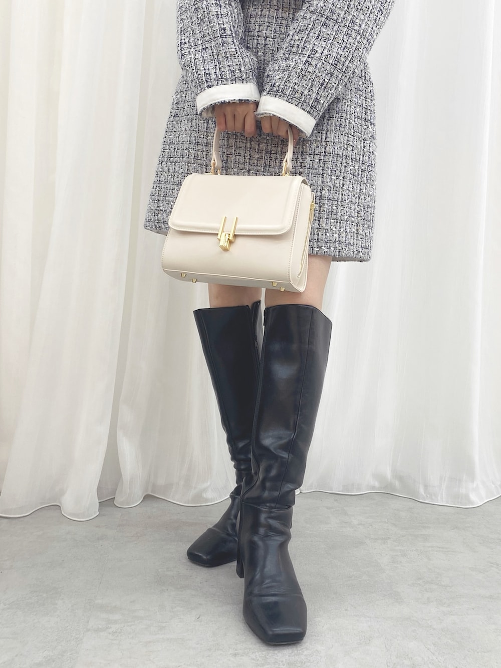 ブラック系のブーツ、ホワイト系のハンドバッグ、ホワイト系のスカートを着用したレディースの秋コーディネートの7枚目の写真