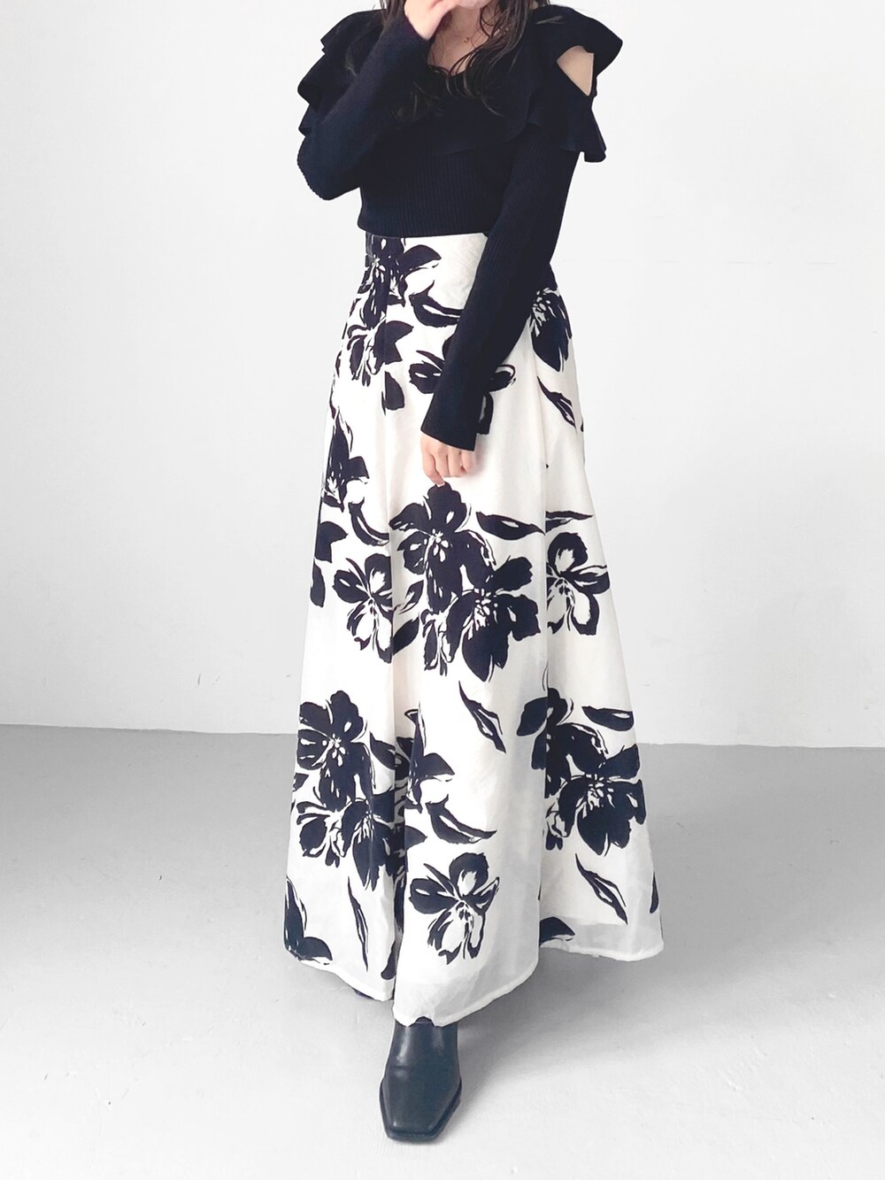 ブラック系のブーツ、ホワイト系のスカート、ブラック系のニット/セーターを着用したレディースの秋コーディネートの4枚目の写真