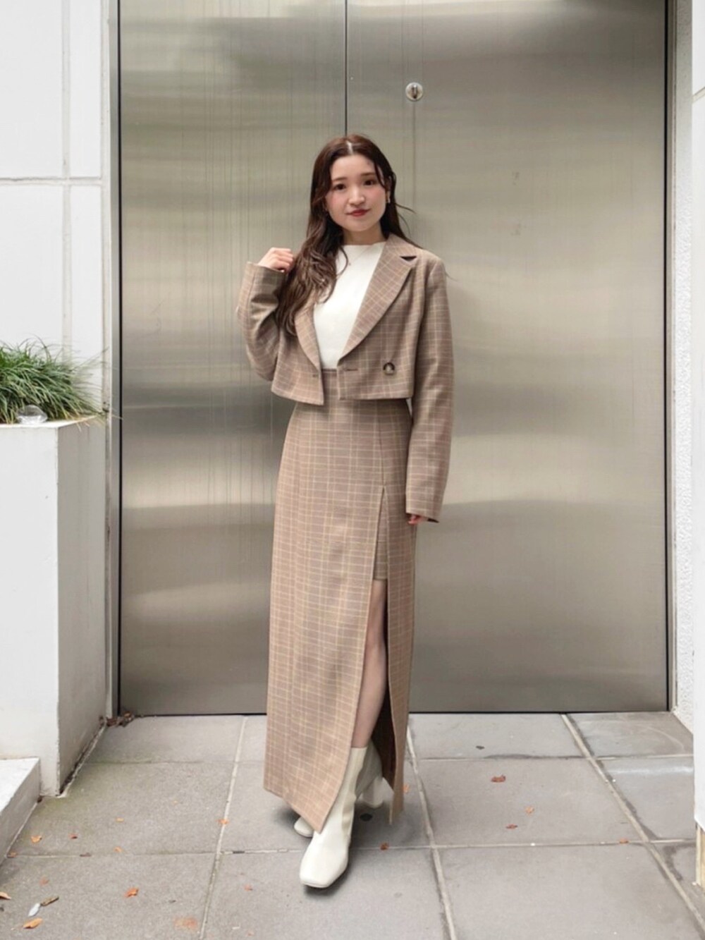 ベージュ系のテーラードジャケット、ベージュ系のスカート、ホワイト系のブーツを着用したレディースの秋コーディネートの2枚目の写真