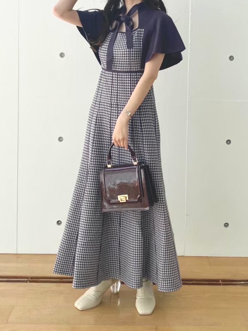 ホワイト系のブーツ、レッド系のハンドバッグ、パープル系のワンピースを着用したレディースの秋コーディネートの2枚目の写真