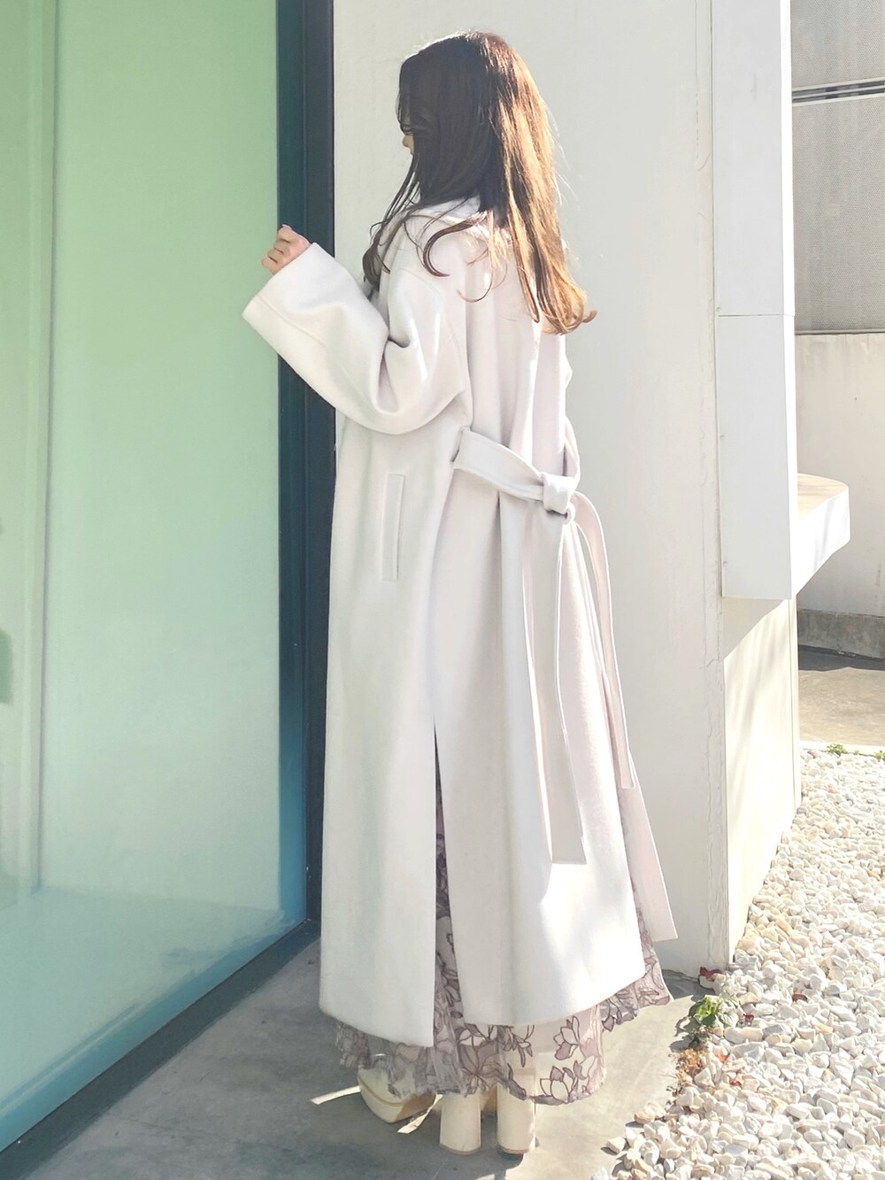 ホワイト系のブーツ、ホワイト系のハンドバッグ、ホワイト系のチェスターコートを着用したレディースの冬コーディネートの5枚目の写真