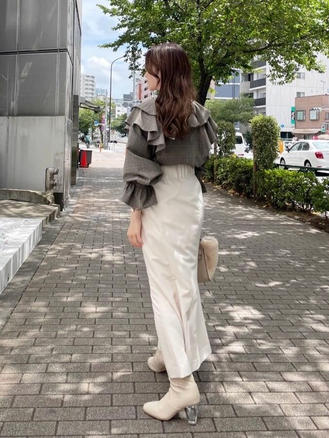 ホワイト系のスカート、ホワイト系のハンドバッグ、ホワイト系のブーツを着用したレディースの秋コーディネートの3枚目の写真