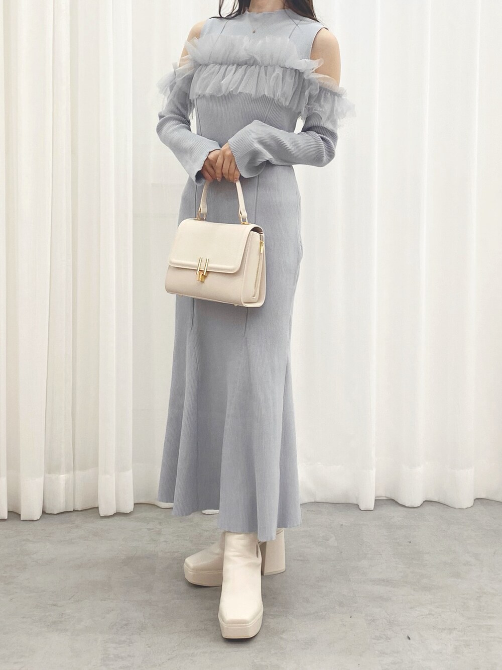 ホワイト系のブーツ、ブルー系のワンピース、ホワイト系のハンドバッグを着用したレディースの秋コーディネートの2枚目の写真