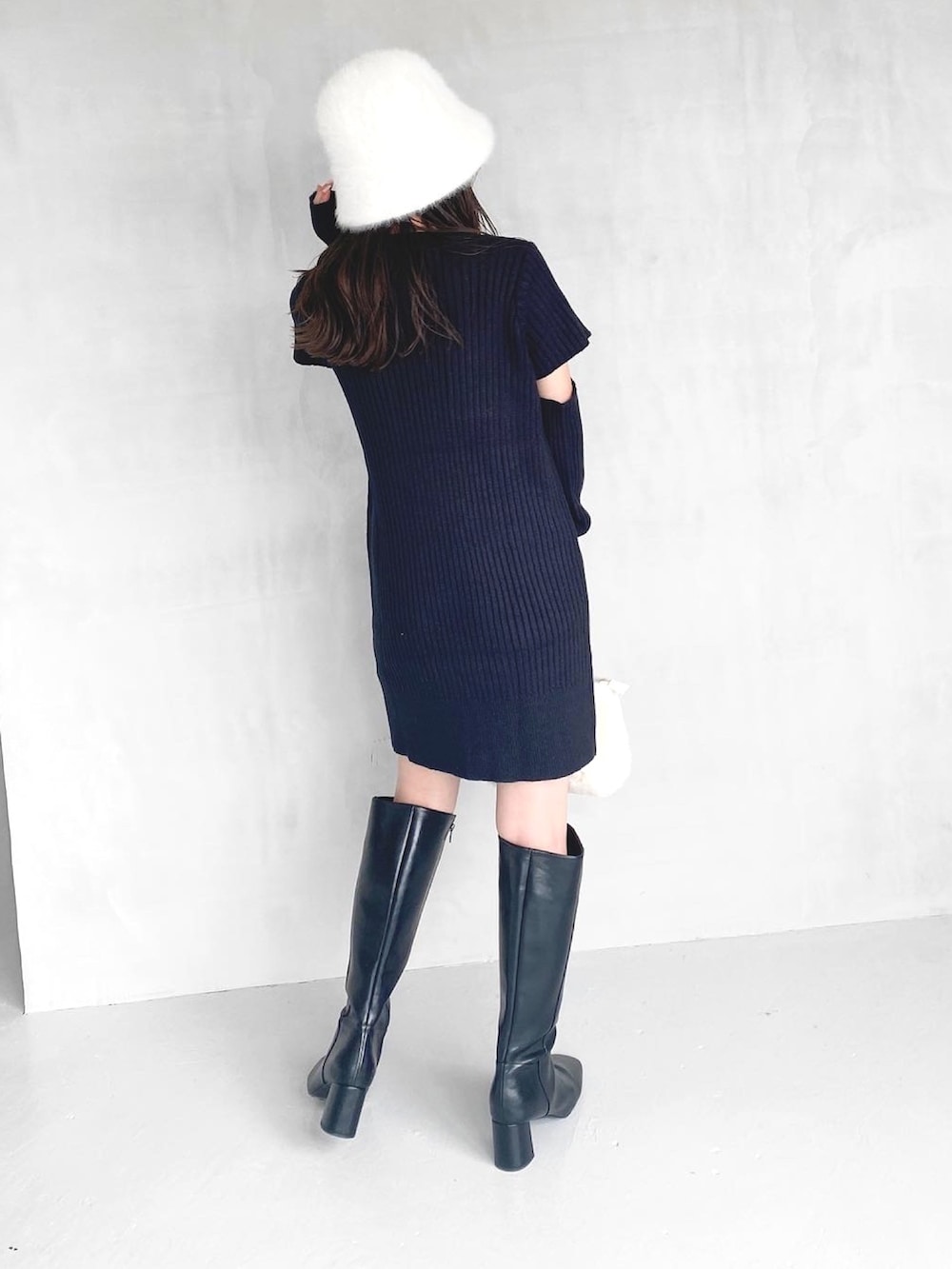 ブラック系のワンピース、ブラック系のブーツ、ホワイト系のハンドバッグを着用したレディースの秋コーディネートの7枚目の写真