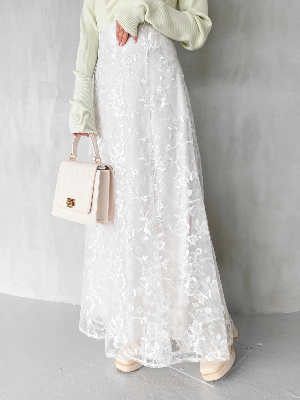 ホワイト系のスカート、ホワイト系のショルダーバッグ、グリーン系のニット/セーターを着用したレディースの秋コーディネートの5枚目の写真