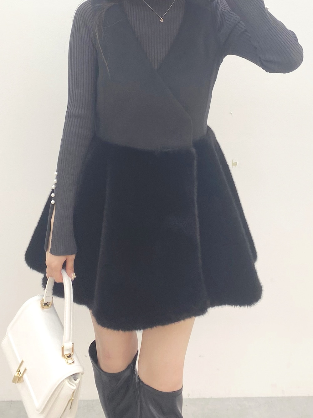 ブラック系のブーツ、ブラック系のワンピース、ホワイト系のハンドバッグを着用したレディースの秋コーディネートの4枚目の写真