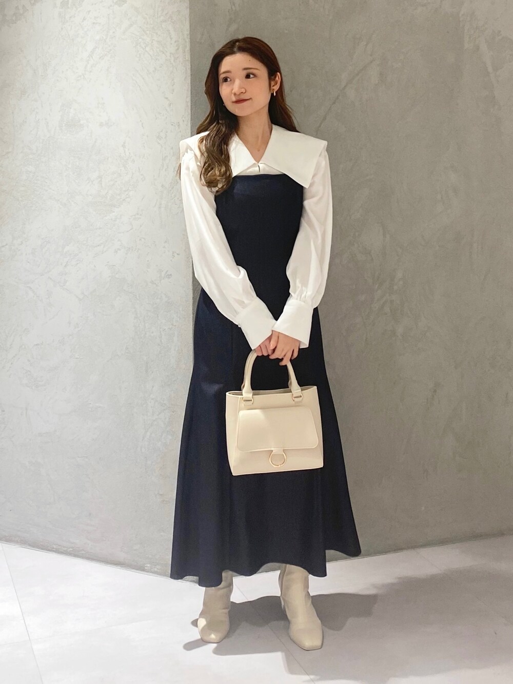 ホワイト系のブーツ、ブルー系のワンピース、ホワイト系のハンドバッグを着用したレディースの冬コーディネートの2枚目の写真