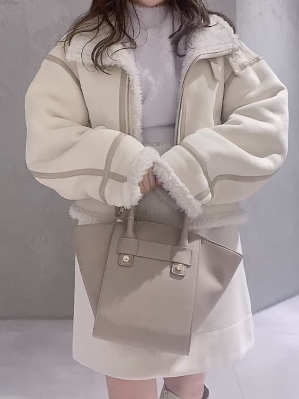 ベージュ系のハンドバッグ、ホワイト系のムートンコート、パープル系のニット/セーターを着用したレディースの冬コーディネートの6枚目の写真