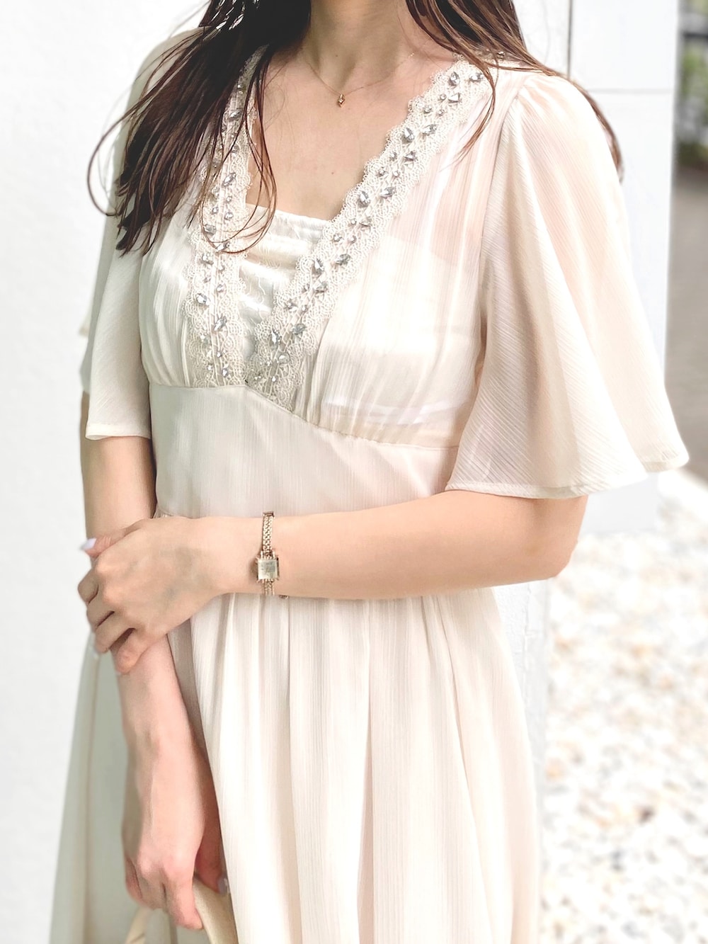 ホワイト系のハンドバッグ、ホワイト系のワンピース、シルバー系のサンダルを着用したレディースの夏コーディネートの4枚目の写真