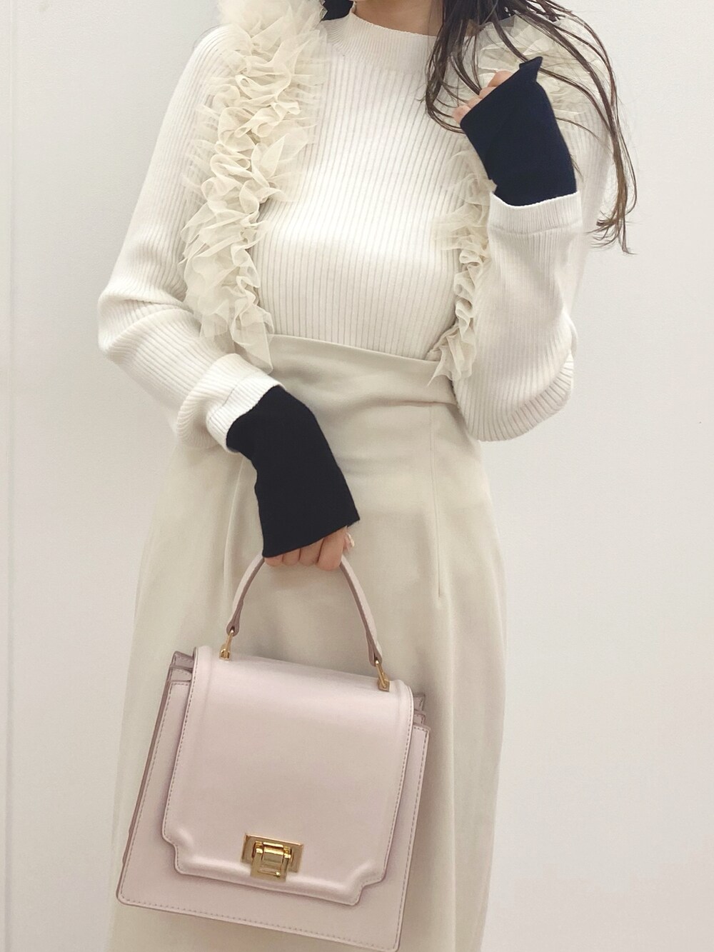 ピンク系のハンドバッグ、ブラック系のブーツ、ホワイト系のスカートを着用したレディースの秋コーディネートの4枚目の写真