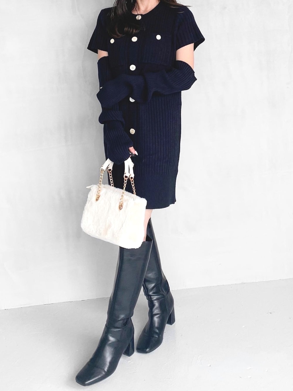 ブラック系のワンピース、ブラック系のブーツ、ホワイト系のハンドバッグを着用したレディースの秋コーディネートの4枚目の写真