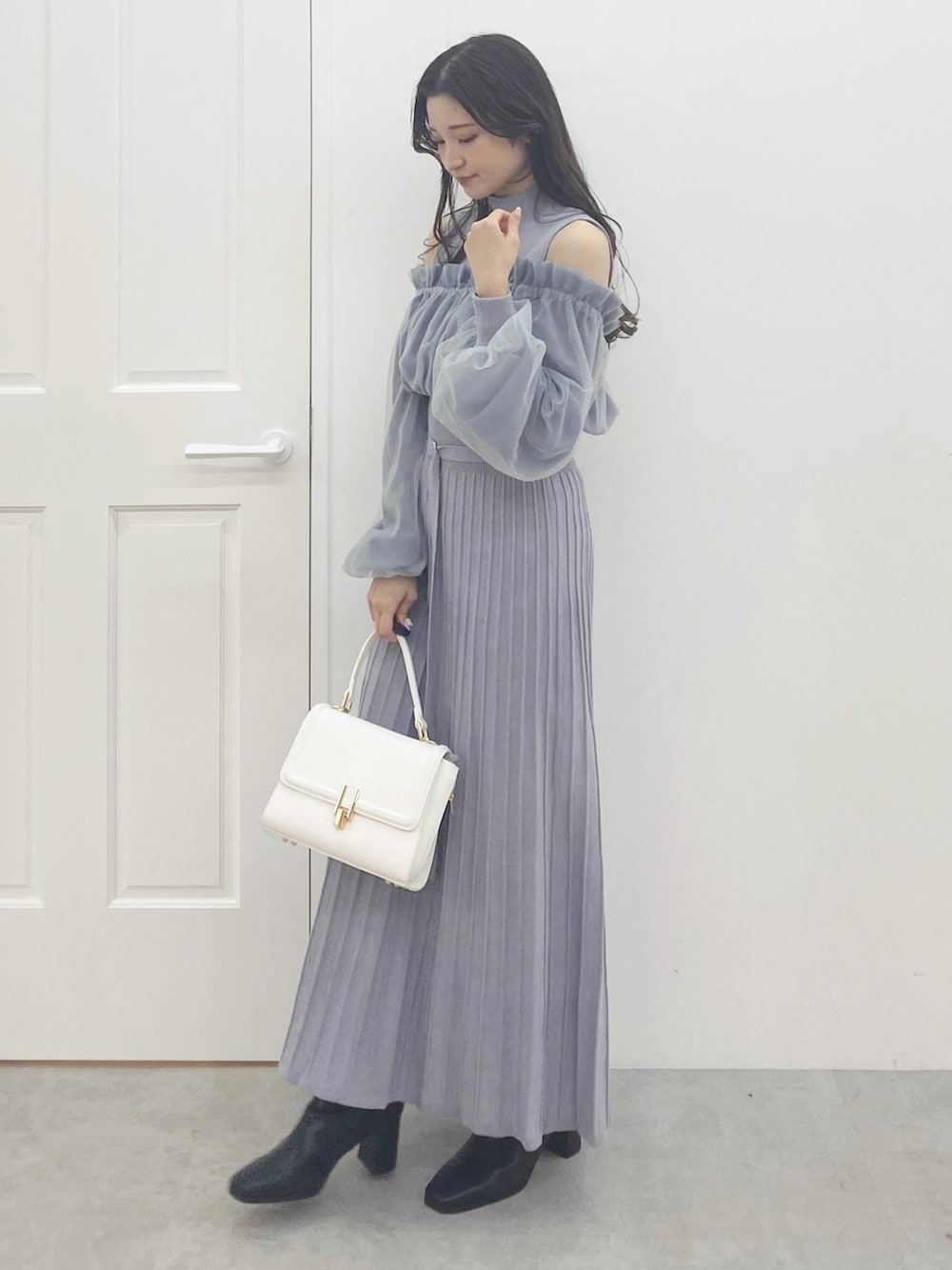 ブラック系のブーツ、ホワイト系のハンドバッグ、ブルー系のワンピースを着用したレディースの秋コーディネートの2枚目の写真