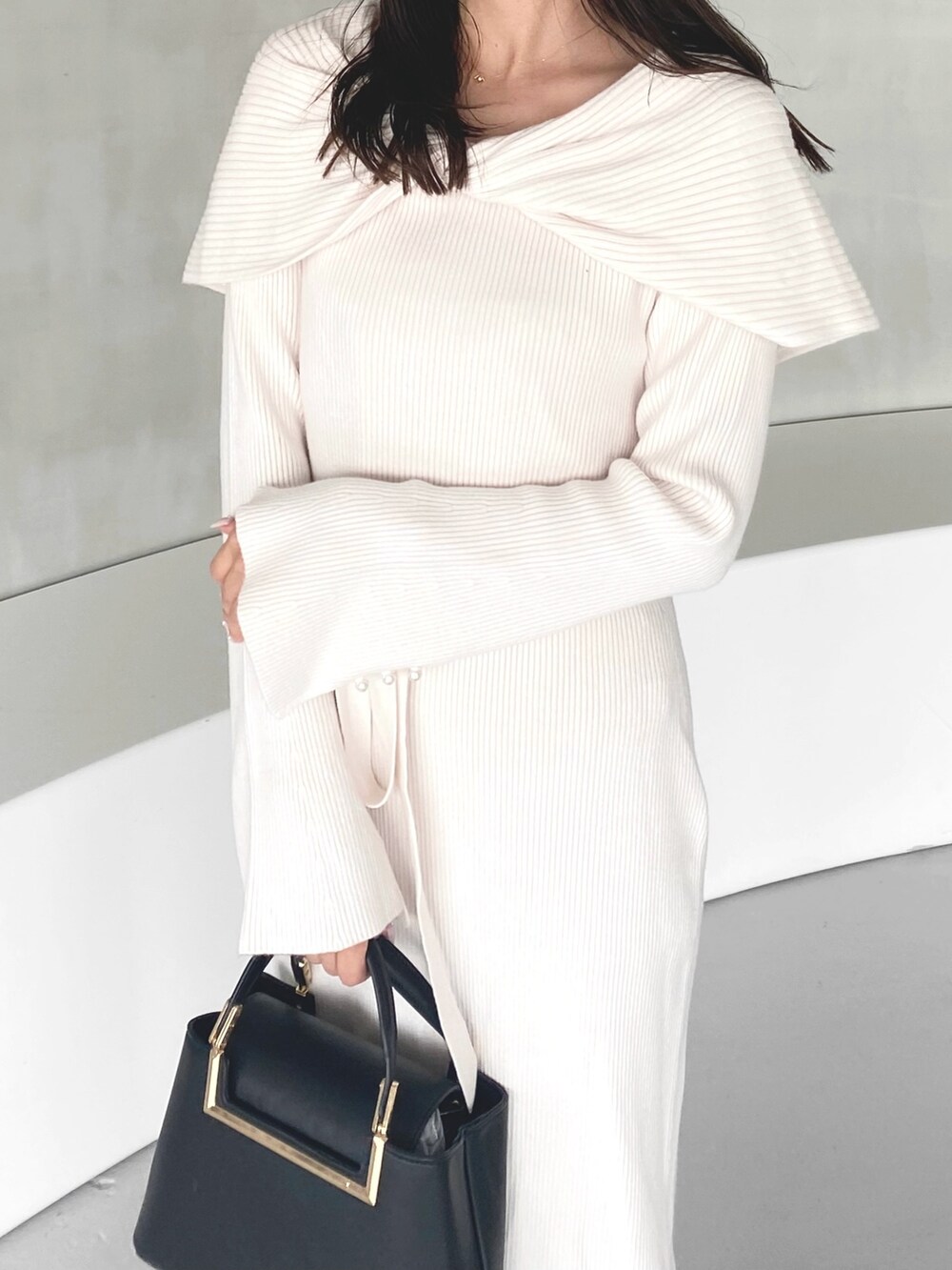 ホワイト系のワンピース、ブラック系のハンドバッグ、ベージュ系のブーツを着用したレディースの冬コーディネートの5枚目の写真