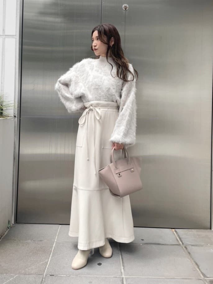 ベージュ系のハンドバッグ、ホワイト系のスカート、ホワイト系のニット/セーターを着用したレディースの秋コーディネートの2枚目の写真