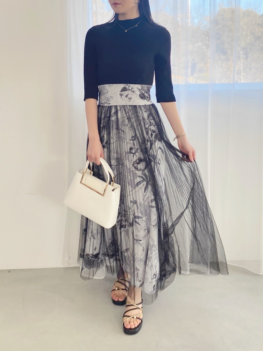 ブラック系のサンダル、ホワイト系のハンドバッグ、ブラック系のワンピースを着用したレディースの春コーディネートの2枚目の写真