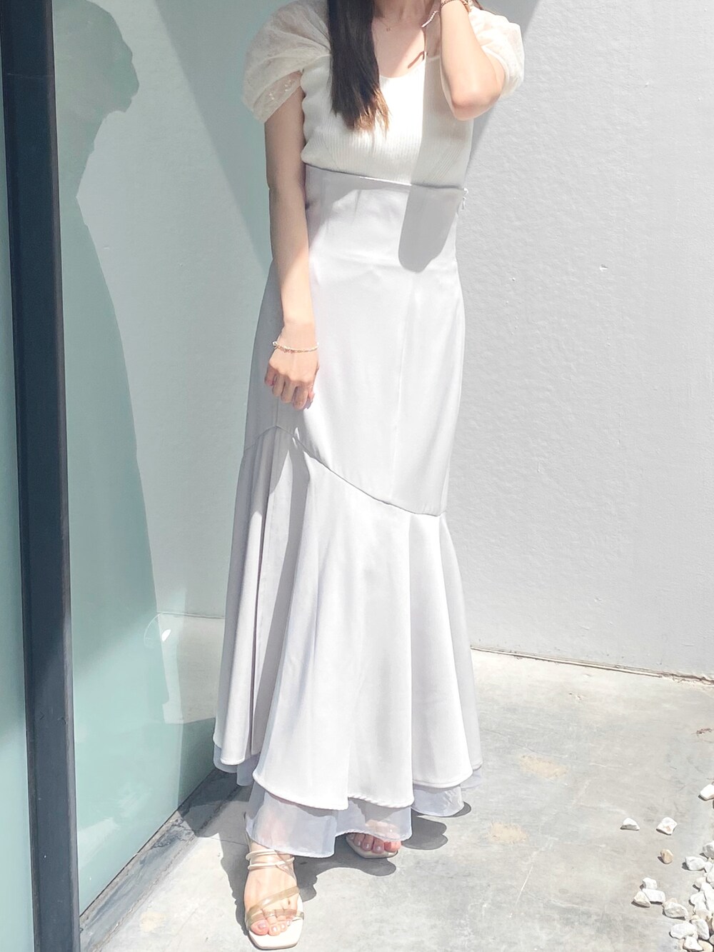 グレー系のスカート、ホワイト系のサンダル、ホワイト系のニット/セーターを着用したレディースの夏コーディネートの2枚目の写真