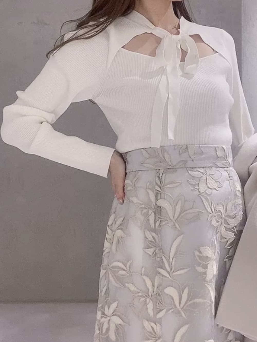 ホワイト系のニット/セーター、ホワイト系のチェスターコート、ブラウン系のハンドバッグを着用したレディースの冬コーディネートの6枚目の写真