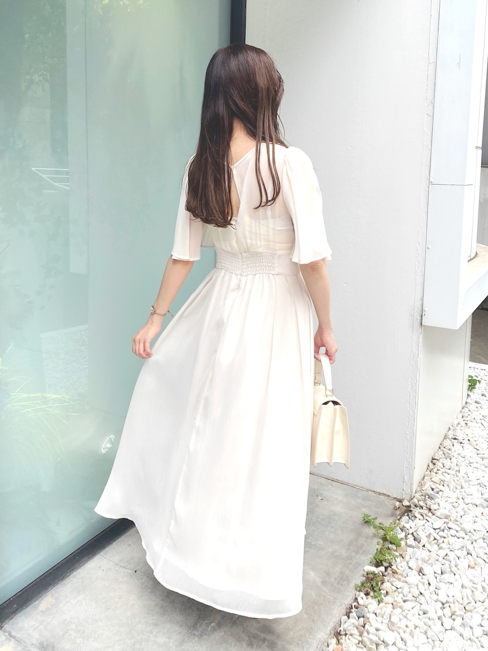 ホワイト系のハンドバッグ、ホワイト系のワンピース、シルバー系のサンダルを着用したレディースの夏コーディネートの5枚目の写真