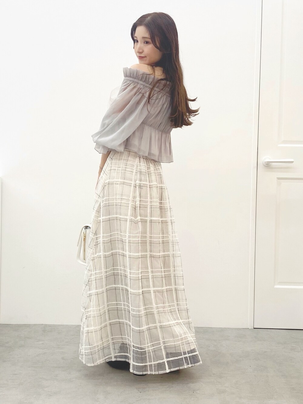 ホワイト系のハンドバッグ、ホワイト系のスカート、ブラック系のブーツを着用したレディースの夏コーディネートの3枚目の写真