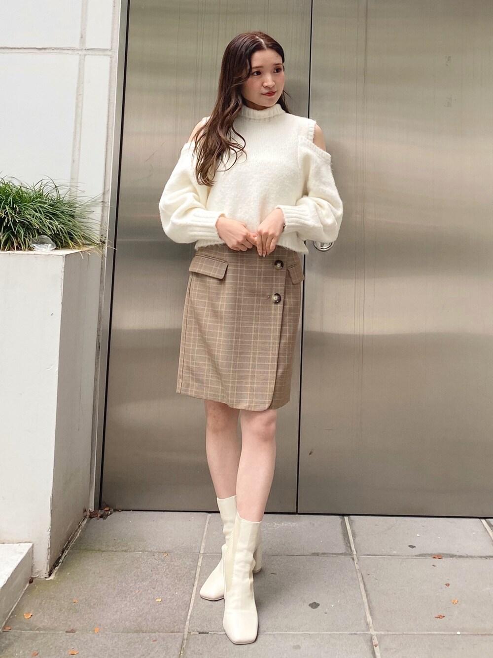 ホワイト系のニット/セーター、ベージュ系のスカート、ホワイト系のブーツを着用したレディースの秋コーディネートの2枚目の写真
