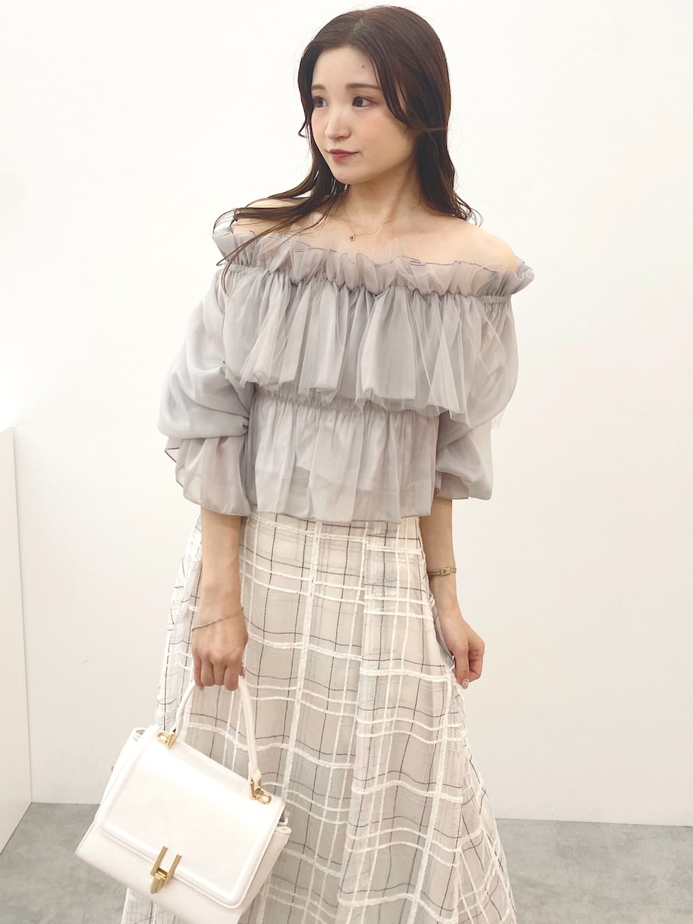 ホワイト系のハンドバッグ、ホワイト系のスカート、ブラック系のブーツを着用したレディースの夏コーディネートの4枚目の写真