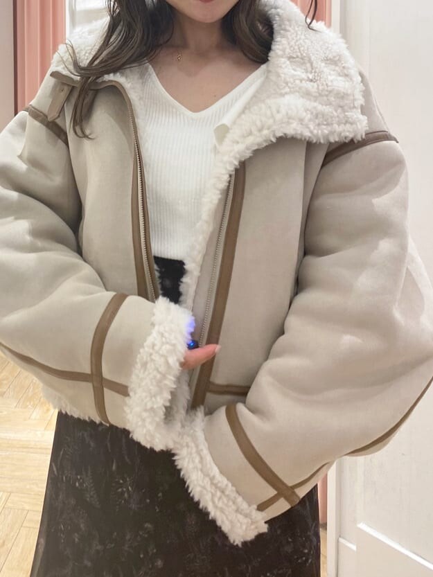 ベージュ系のムートンコート、ブラック系のブーツ、ホワイト系のニット/セーターを着用したレディースの秋コーディネートの7枚目の写真