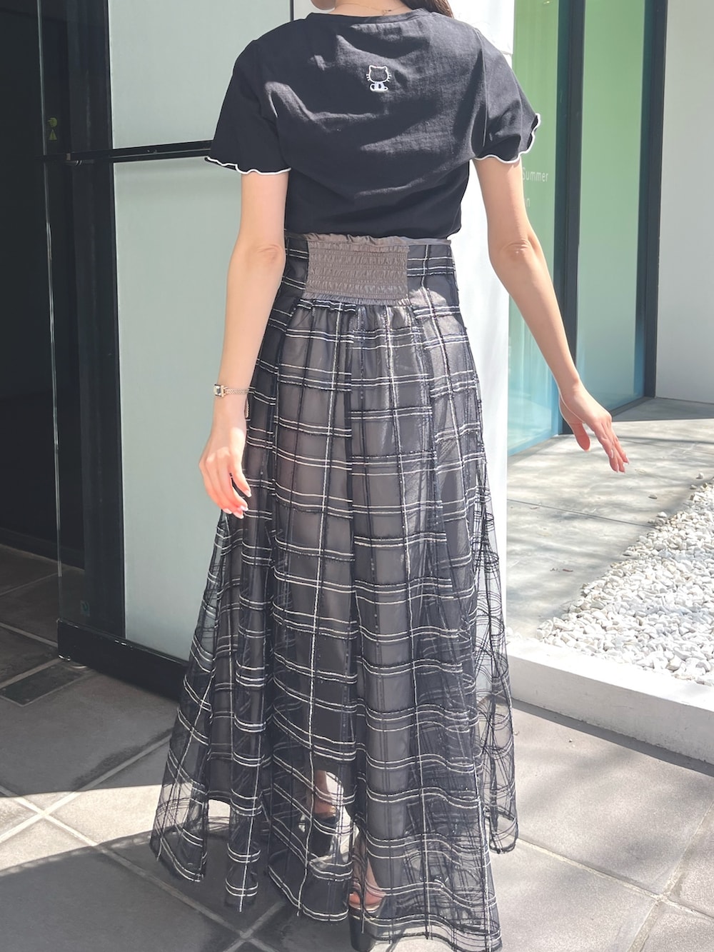 ブラック系のサンダル、ブラック系のスカート、ブラック系のTシャツ/カットソーを着用したレディースの春コーディネートの5枚目の写真