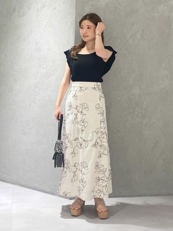 ブラック系のショルダーバッグ、ブラック系のニット/セーター、ホワイト系のスカートを着用したレディースの夏コーディネートの4枚目の写真