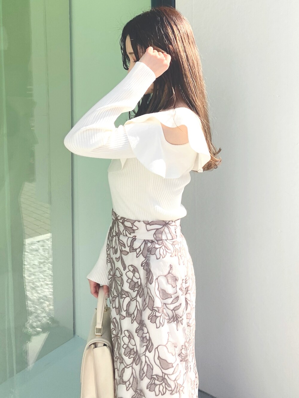 ホワイト系のブーツ、ホワイト系のニット/セーター、ホワイト系のハンドバッグを着用したレディースの冬コーディネートの3枚目の写真