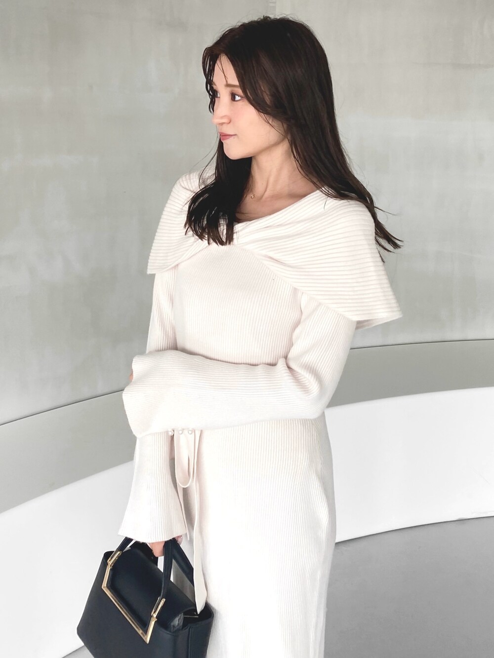 ホワイト系のワンピース、ブラック系のハンドバッグ、ベージュ系のブーツを着用したレディースの冬コーディネートの4枚目の写真