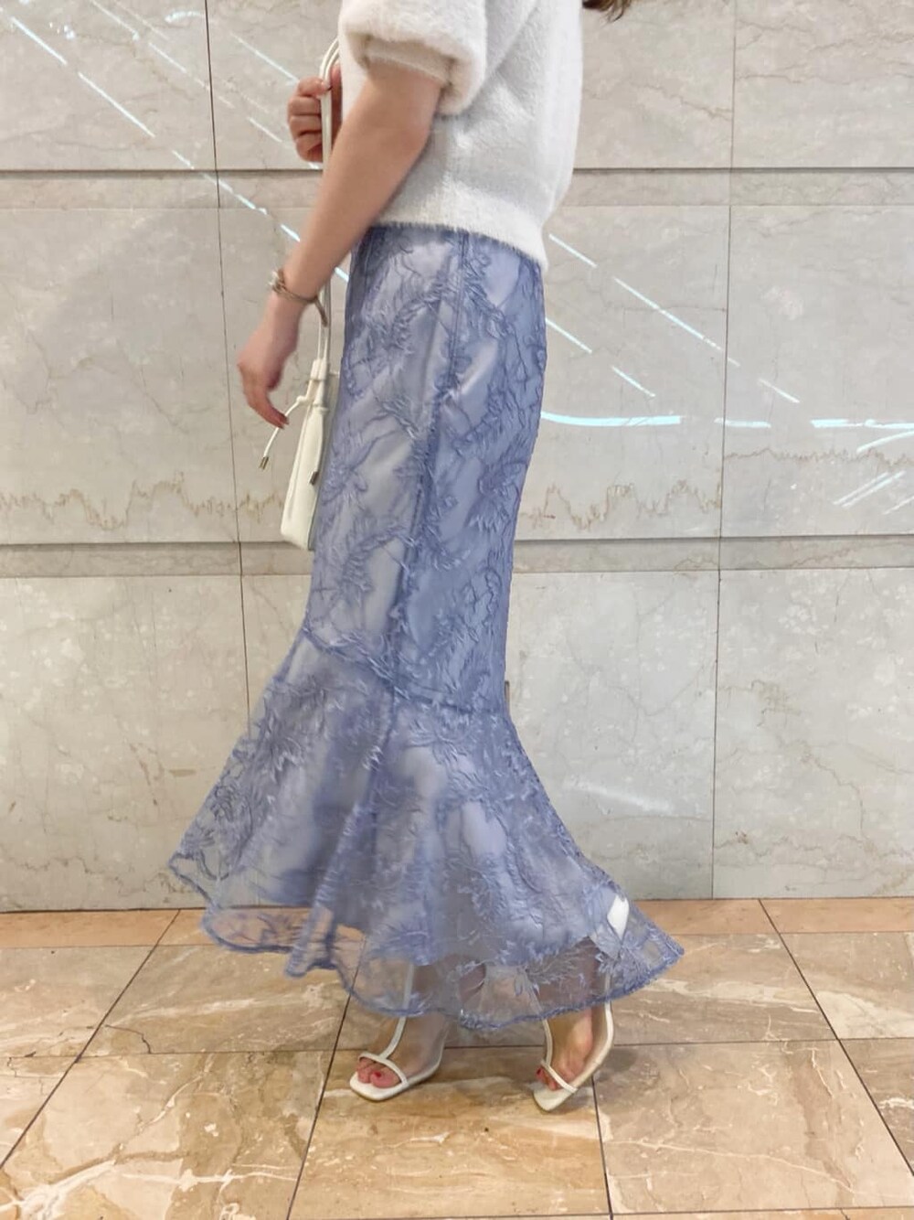 ブルー系のスカート、ホワイト系のその他シューズ、ベージュ系のショルダーバッグを着用したレディースの夏コーディネートの3枚目の写真