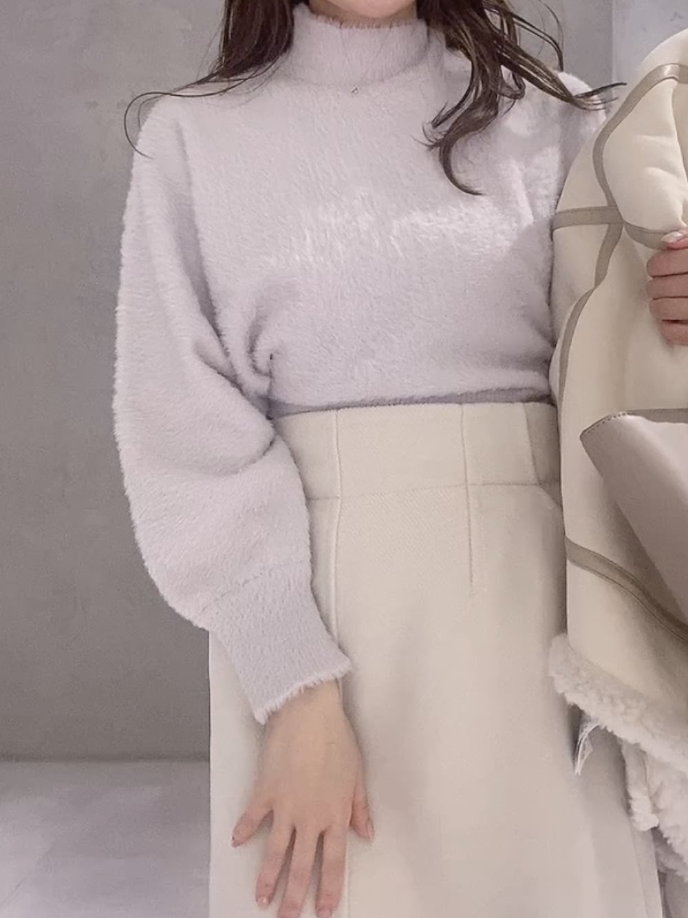 ベージュ系のハンドバッグ、ホワイト系のムートンコート、パープル系のニット/セーターを着用したレディースの冬コーディネートの8枚目の写真