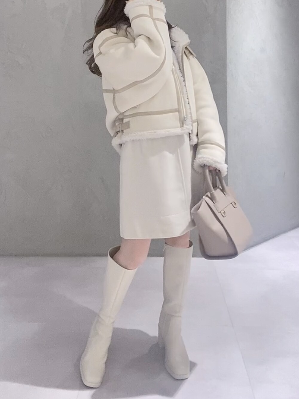 ベージュ系のハンドバッグ、ホワイト系のムートンコート、パープル系のニット/セーターを着用したレディースの冬コーディネートの4枚目の写真