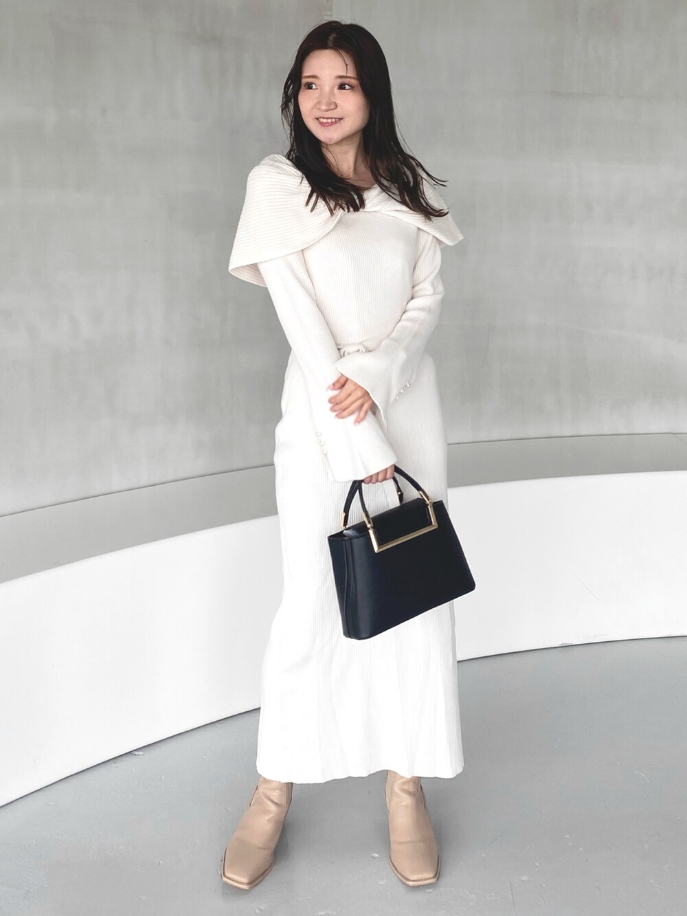 ホワイト系のワンピース、ブラック系のハンドバッグ、ベージュ系のブーツを着用したレディースの冬コーディネートの3枚目の写真